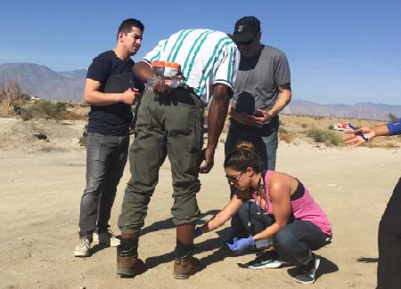 Two doctors and a nurse treat a homeless man with a leg injury.