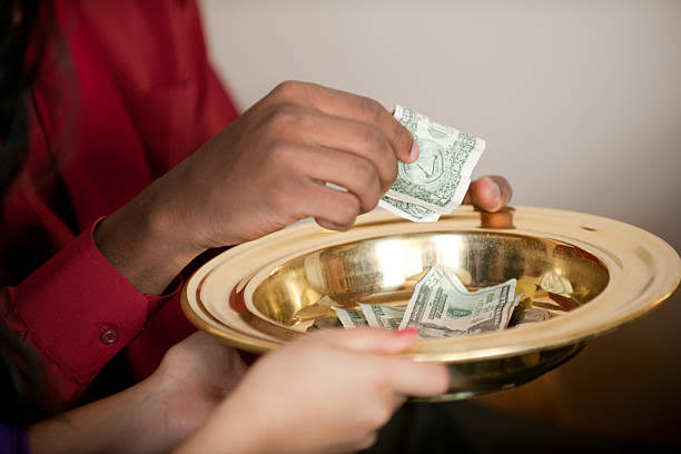 A person placing a monetary donation into a gold plate in worship service.